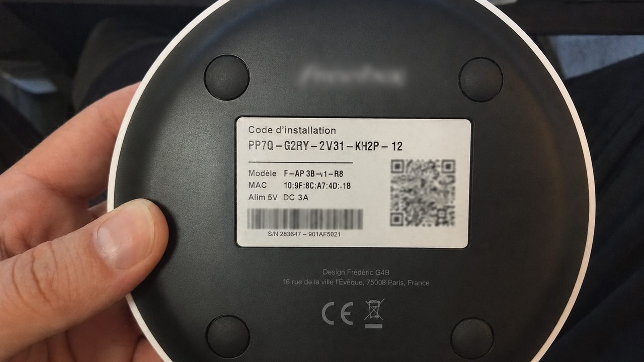 Dessous d'une box internet : étiquette avec code d'installation, modèle, adresse MAC et numéro de série.